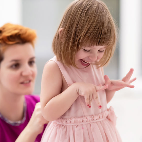 A woman helps a little girl with her dress, highlighting a moment of assistance and guidance.