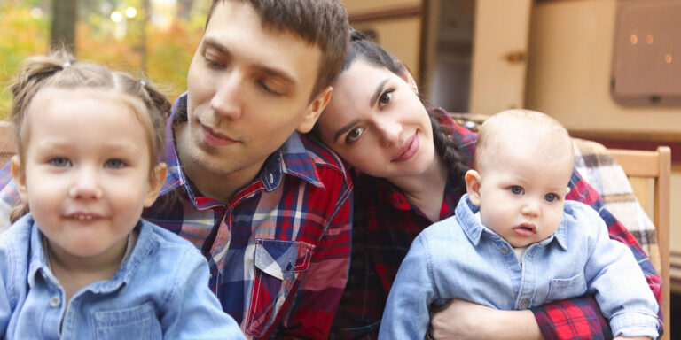 A family of four seated on a couch smiling and enjoying family time together.